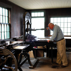 man using printing press at mystic seaport museum