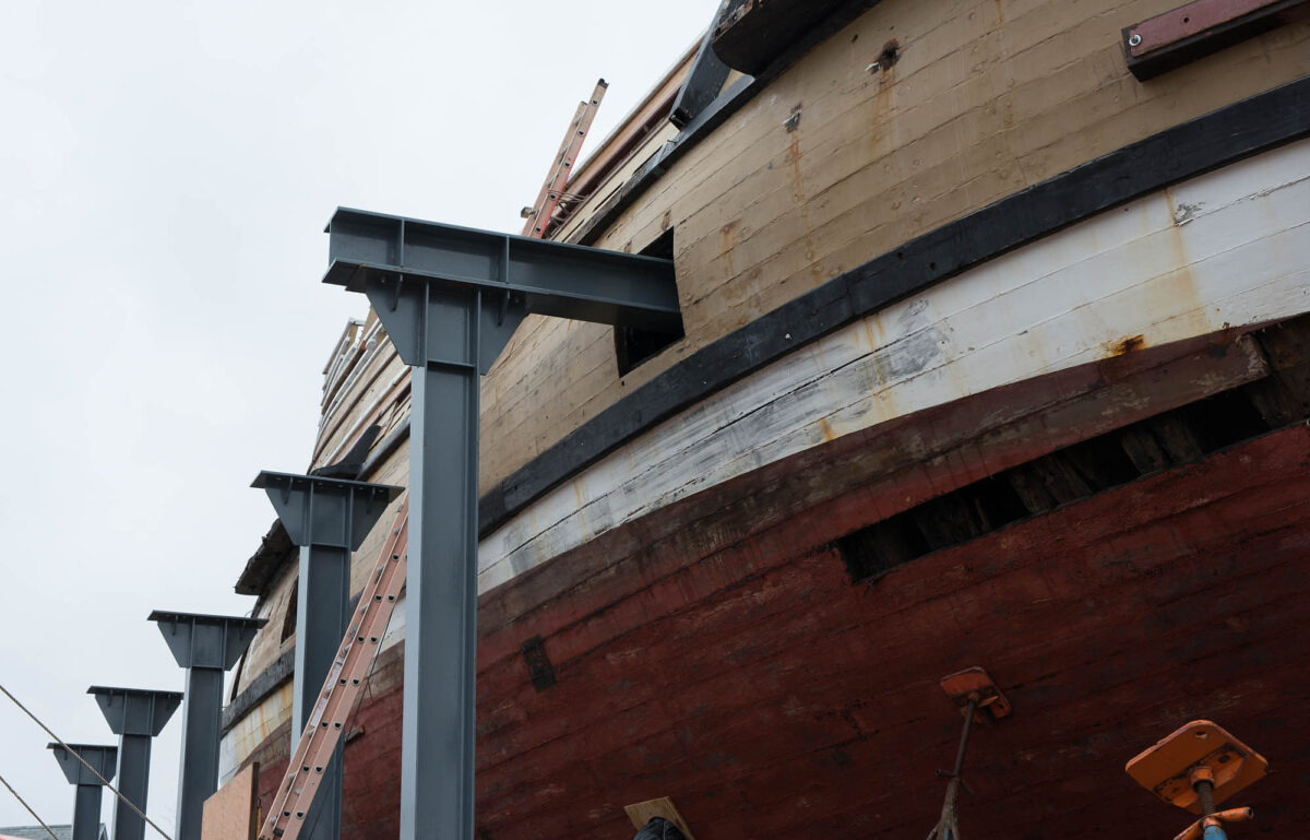 The steel beams pass through the gunports to another vertical support on the other side of the ship.