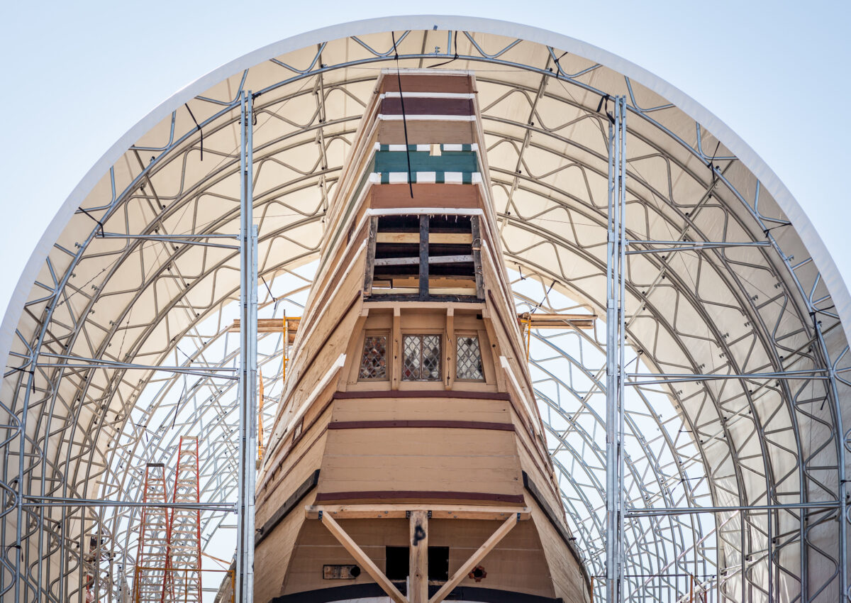 MAYFLOWER II's stern peeks out from underneath the temporary structure nicknamed "the Mailbox."