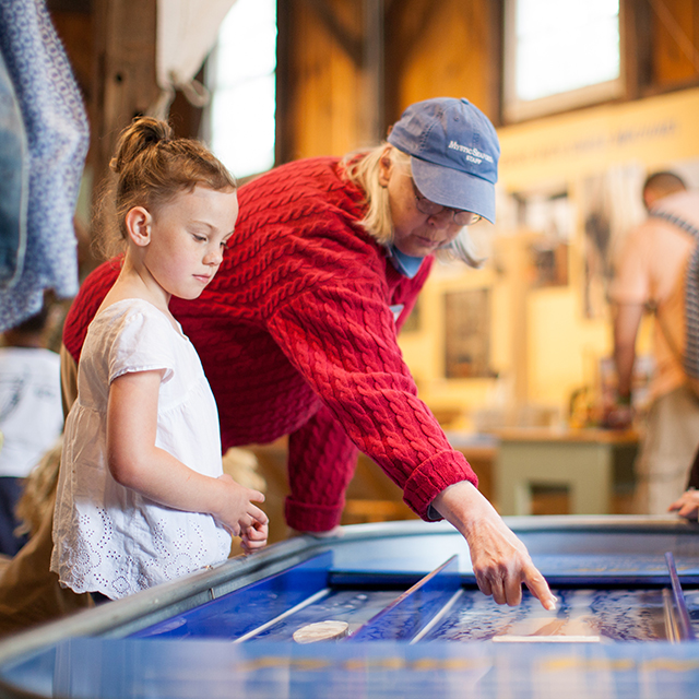 woman pointing to exhibit as small child looks on at mystic seaport mus